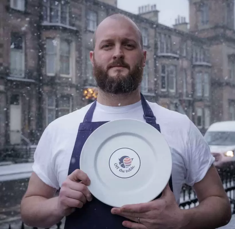 Off the table - Edinburgh based Chef holds plate with off the table branding